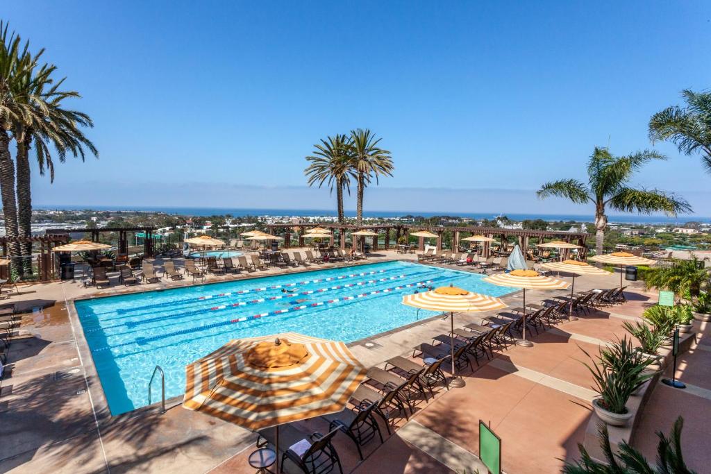 a swimming pool with umbrellas and tables and chairs at Grand Pacific Palisades Resort in Carlsbad