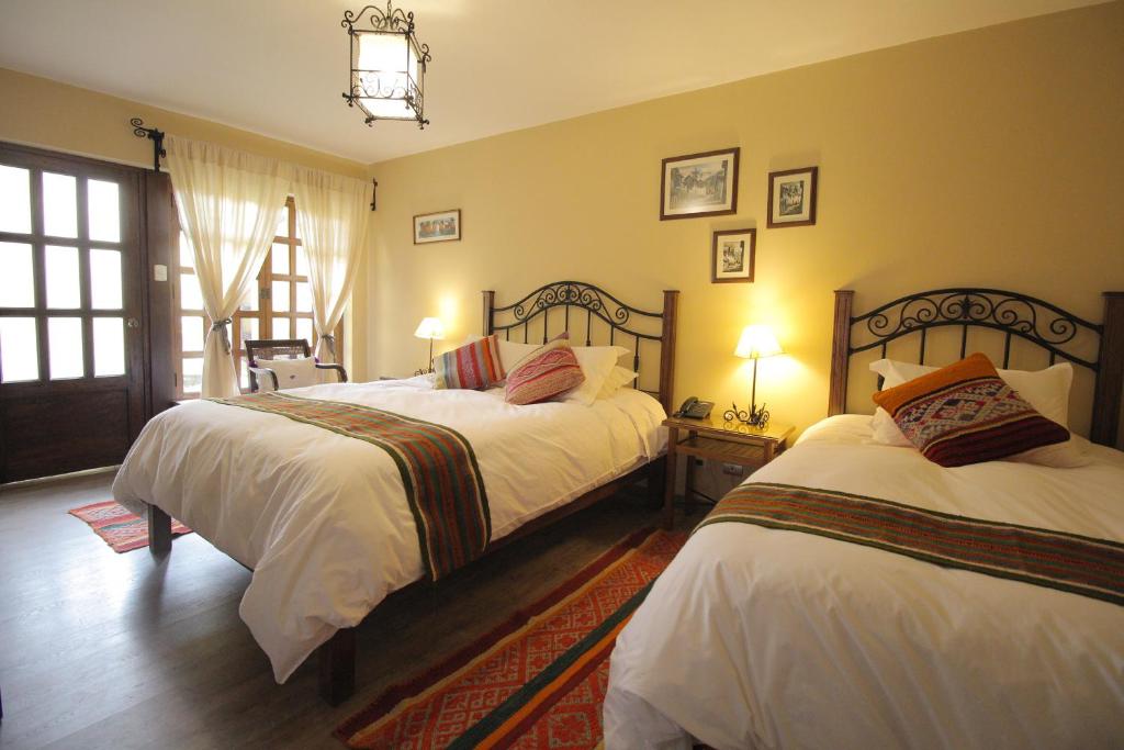 1 dormitorio con 2 camas con sábanas blancas y ventana en LLipimpac House, en Cusco