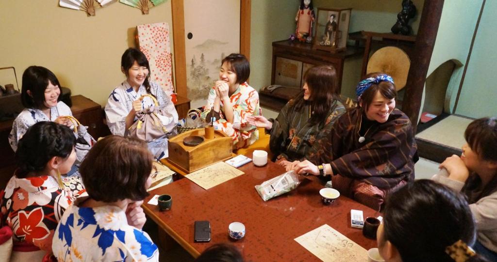 een groep mensen die rond een tafel zitten bij Japanese Guesthouse Kinosaki Wakayo (Female Only) in Toyooka