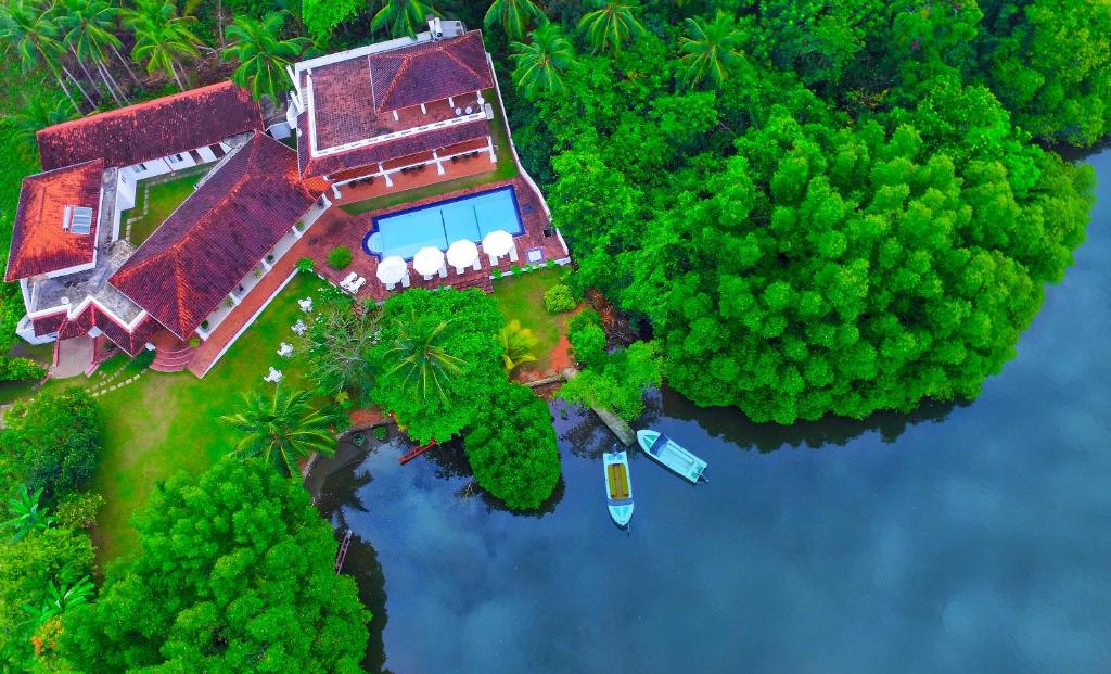 an island with a house and a boat in the water at Waterside Bentota in Bentota