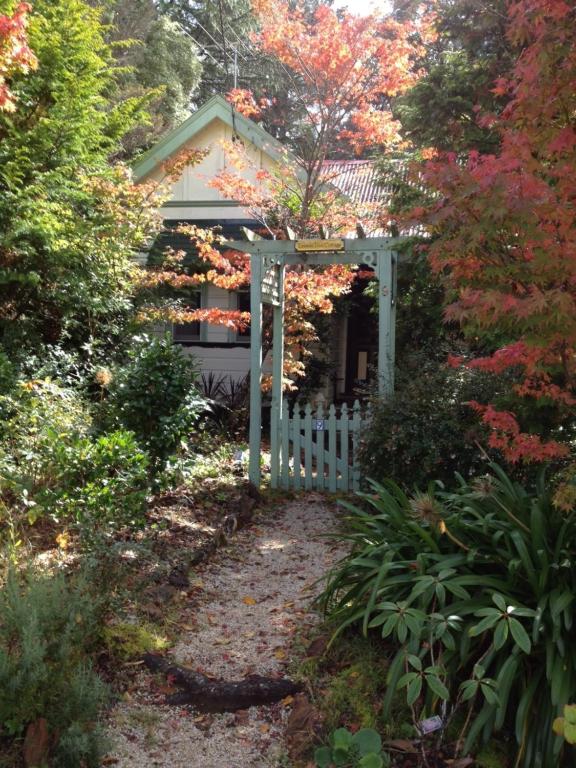 a garden entrance to a house with a white gate at Lemon Tree Cottage in Leura