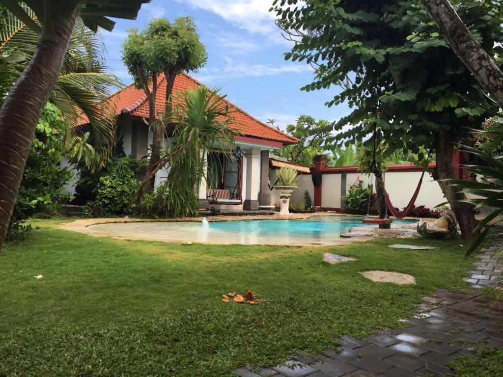 a house with a swimming pool in a yard at Villa Shantitara Bungalows in Sanur