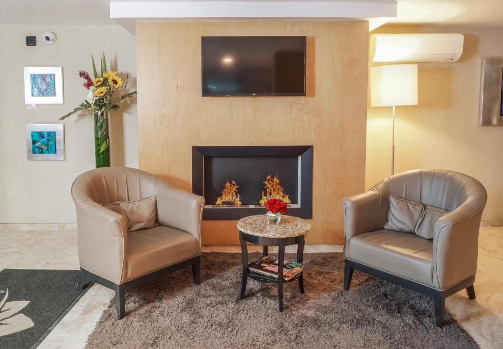 A hotel sitting area with two armchairs, a television and a decorative fireplace.
