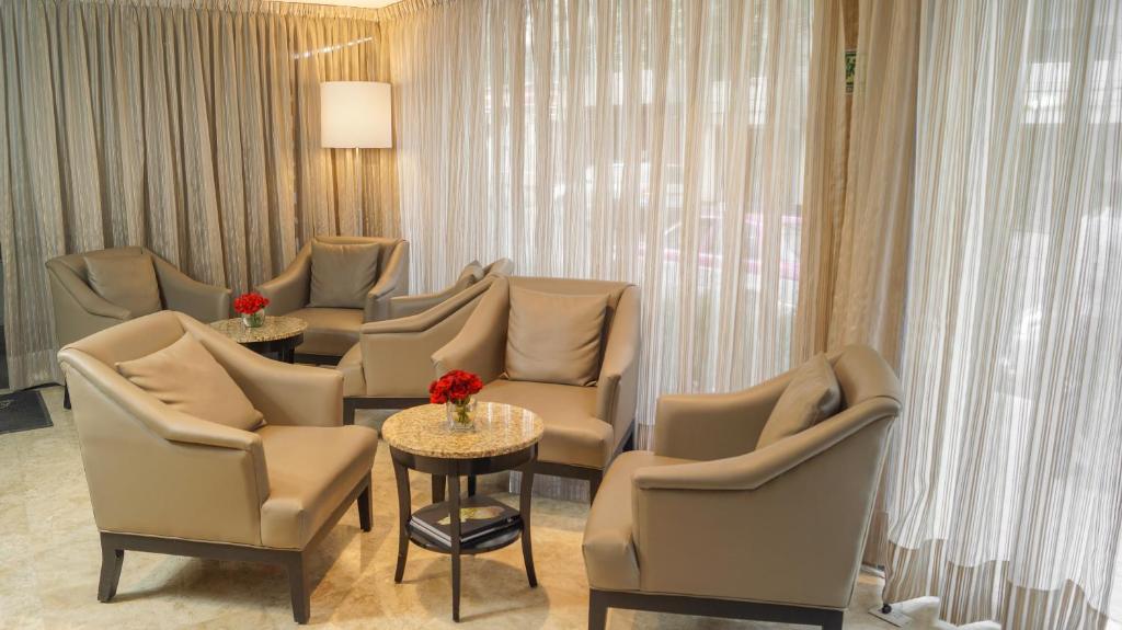A curtained lounge with upholstered armchairs grouped around small tables.