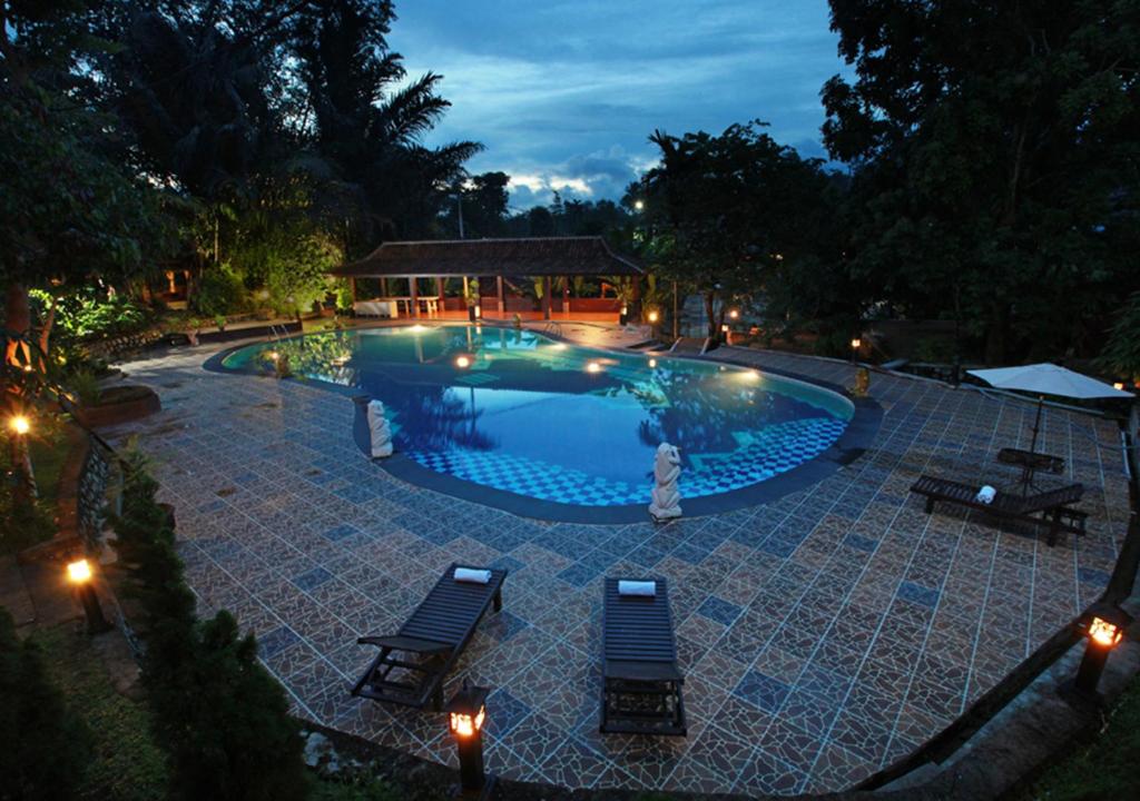 a swimming pool at night with two chairs and lights at Green Tropical Village in Tanjungpandan