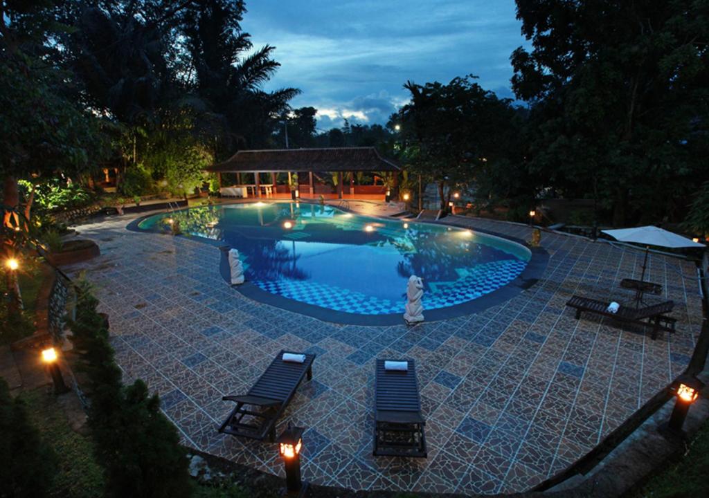 una piscina por la noche con 2 sillas y luces en Green Tropical Village, en Tanjung Pandan