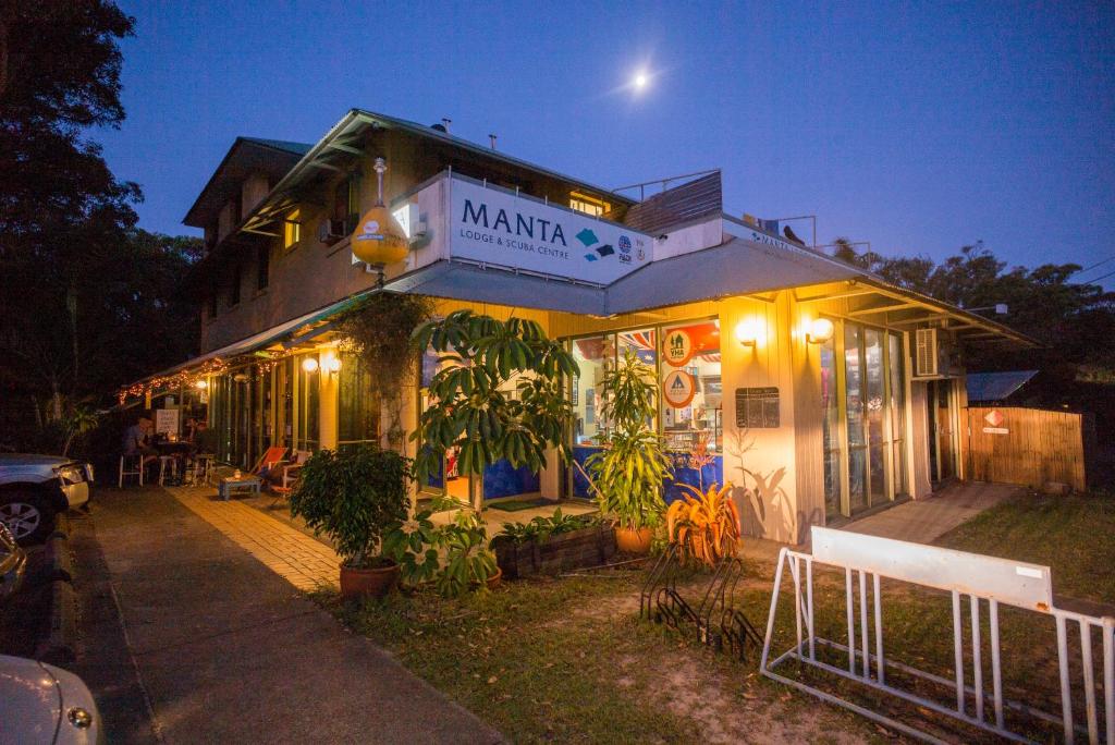 una casa con un cartel que lee manillaarma por la noche en Manta Lodge YHA & Scuba Centre en Point Lookout