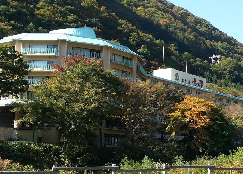 a building on the side of a hill with trees at Hotel Yunojin in Minakami