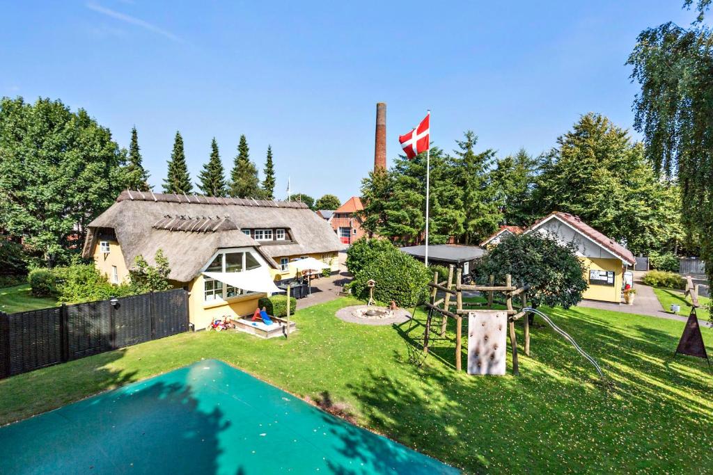 uma imagem de uma casa com uma bandeira no quintal em Omme Å Camping & Cottages em Sønder Omme