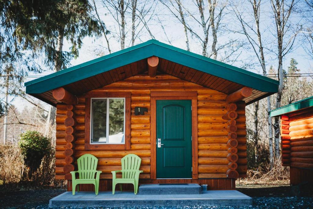 um chalé de madeira com duas cadeiras e uma porta em Port Hardy Cabins em Port Hardy