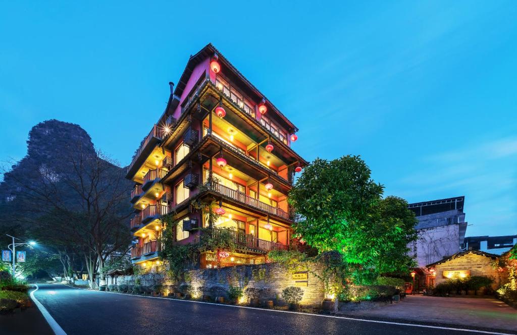 a tall building with lights on the side of a street at Yangshuo Mountain Nest Boutique Hotel in Yangshuo