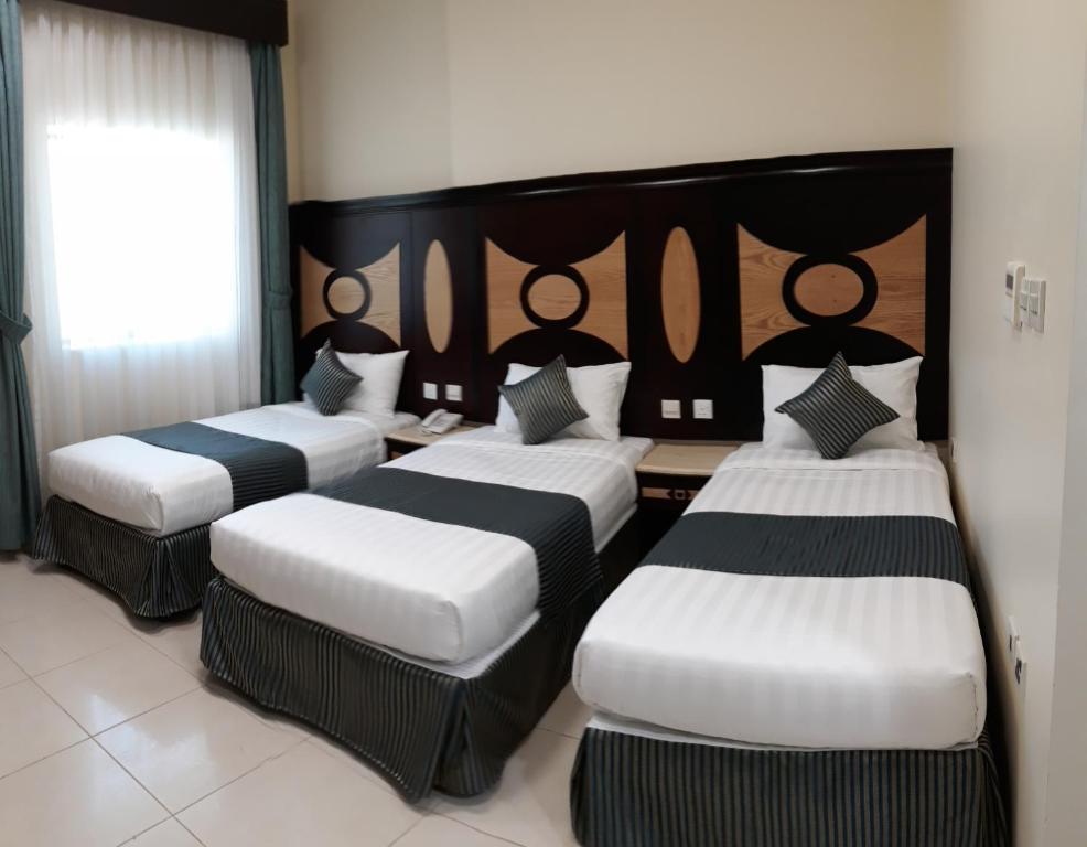 a room with three beds with black and white sheets at فندق ديار المشاعر in Makkah