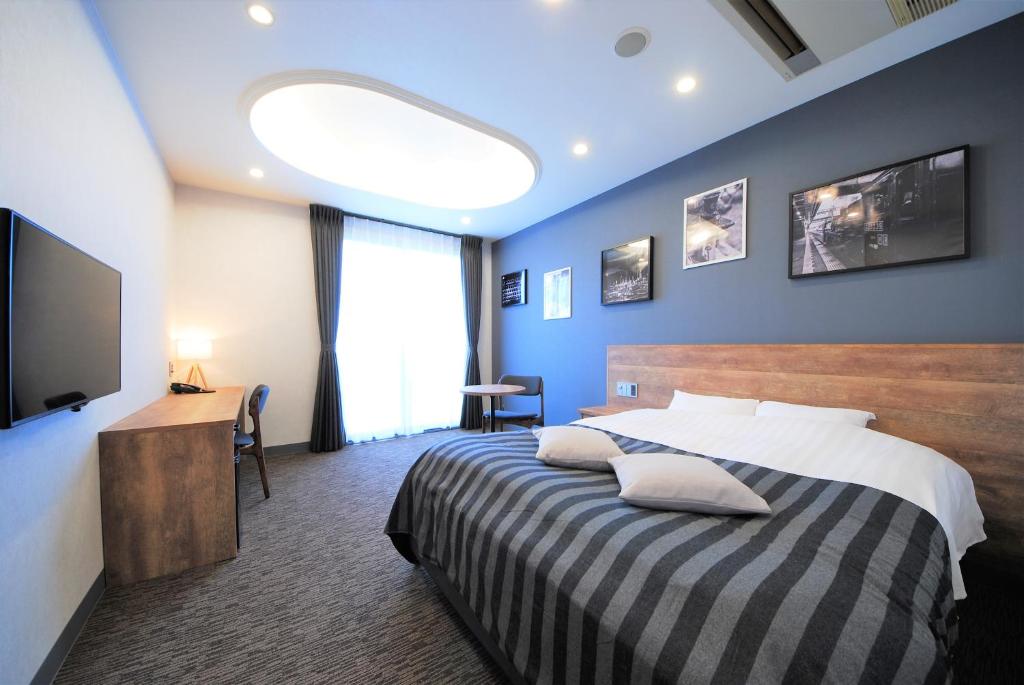 um quarto de hotel com uma cama e uma televisão em Hotel cooju Fukui em Sakai