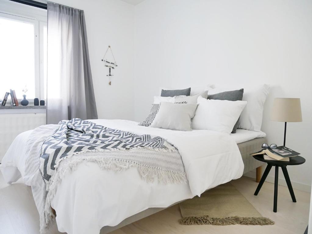 a white bedroom with a bed with white sheets and pillows at Roost Kristian in Helsinki