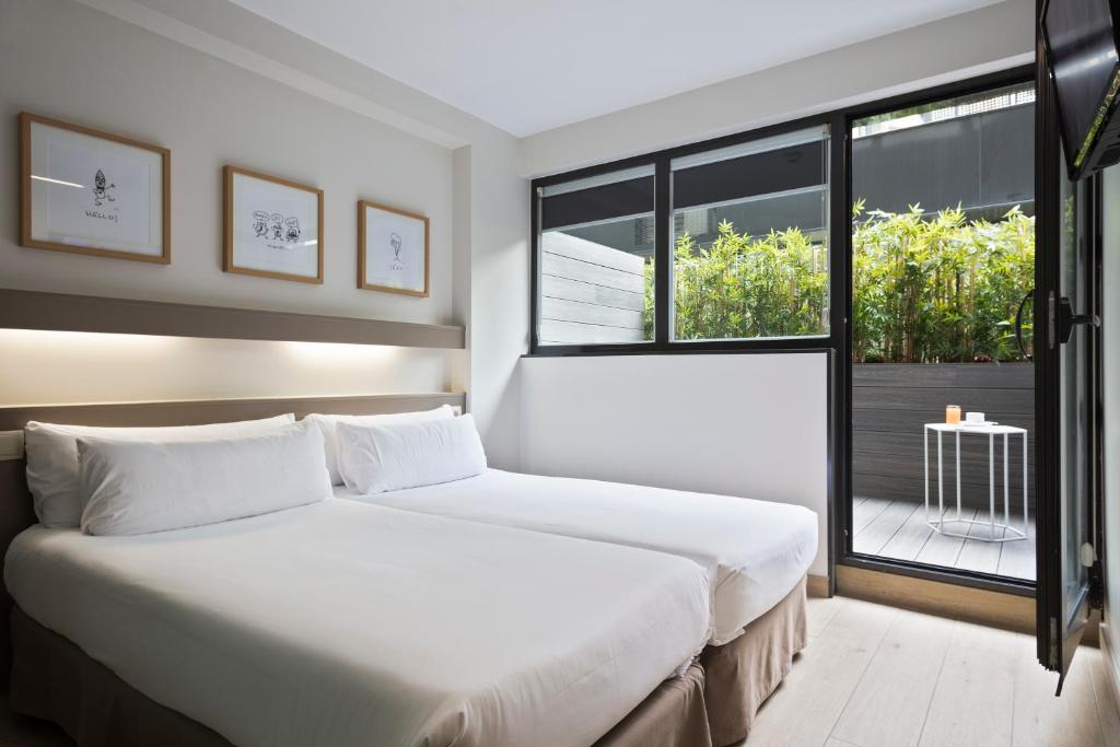 Un dormitorio con una gran cama blanca y una ventana en Aparthotel Bcn Montjuic en Barcelona