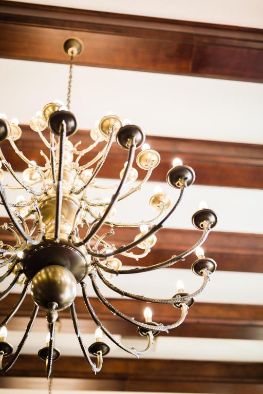 Brass multi-arm chandelier with lit bulbs against wood-beamed ceiling, elegant lighting detail