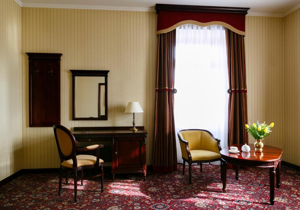 Sunlit hotel sitting room with striped curtains, two yellow chairs and table with tea