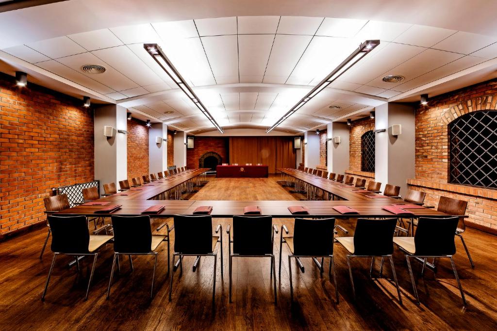 Spacious U-shaped conference room with wooden tables, many chairs, exposed brick walls