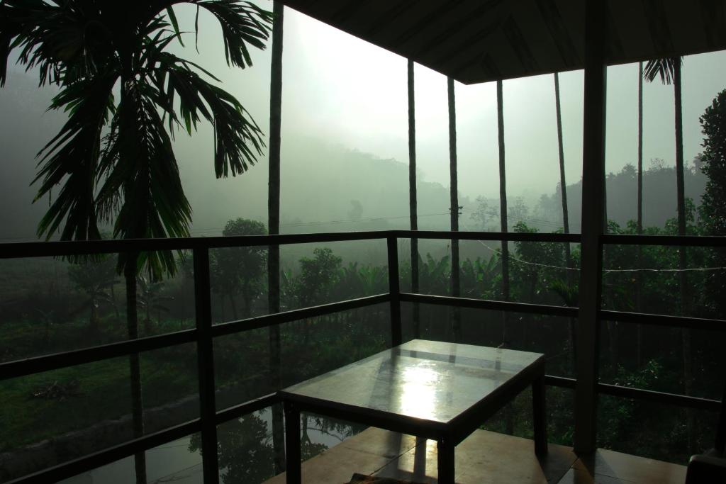 a balcony with a table and a view of a forest at ExoticaHolidays in Sultan Bathery
