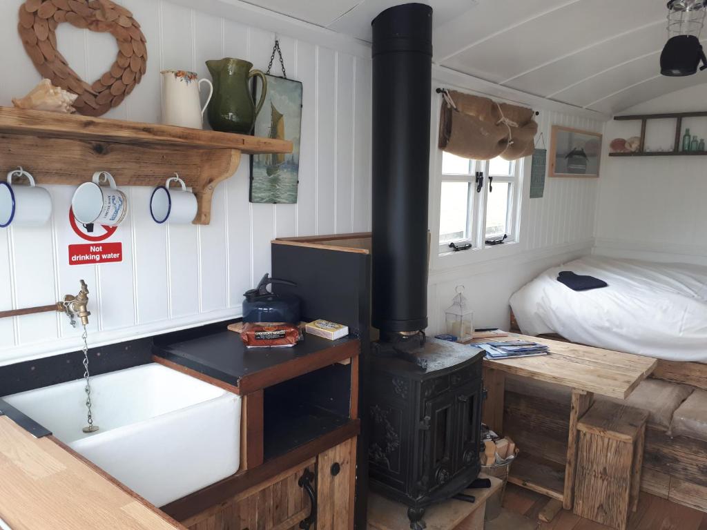 a kitchen with a stove in a room with a bed at Meadowbeck - Shepherd Huts in Fylingdales