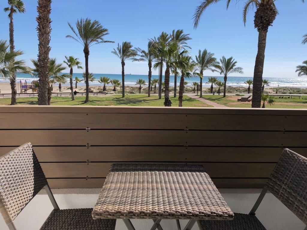 un banco y sillas en un balcón con vistas a la playa en Hotel Costa Azahar, en Grao de Castellón
