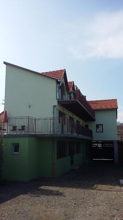 Pensiunea Casa Szabi في Luna de Sus: مبنى أخضر وبيضاء مع شرفة