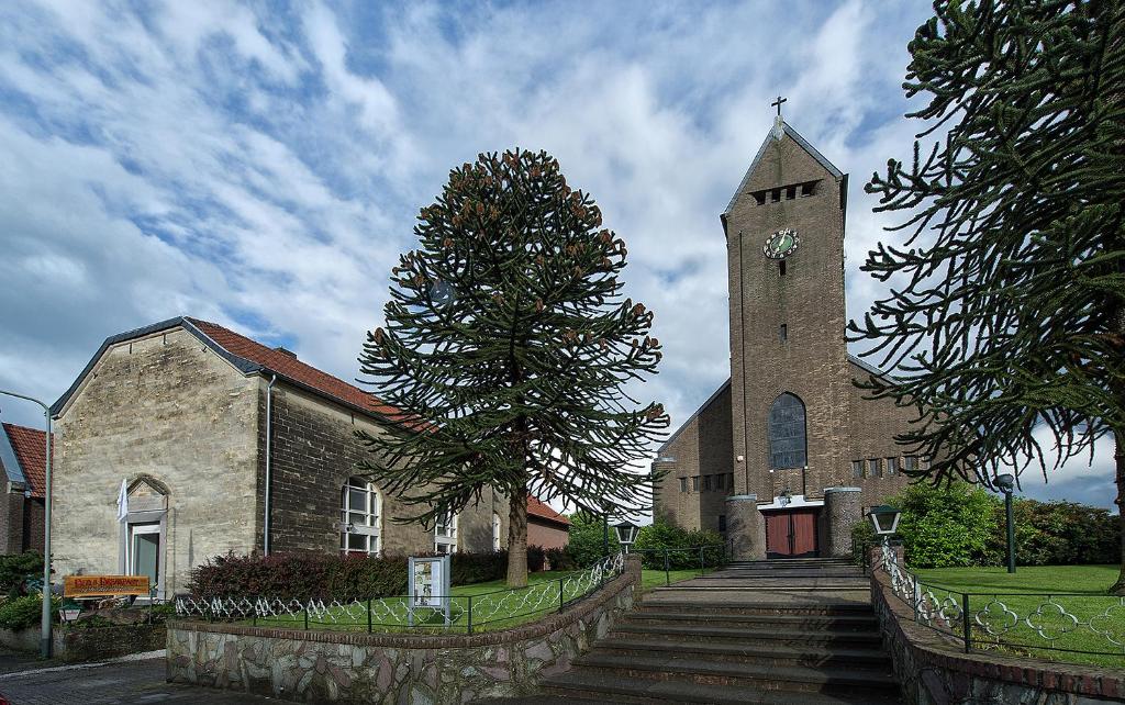 uma igreja com uma torre com um relógio em B&B In de zevende hemel em Reijmerstok