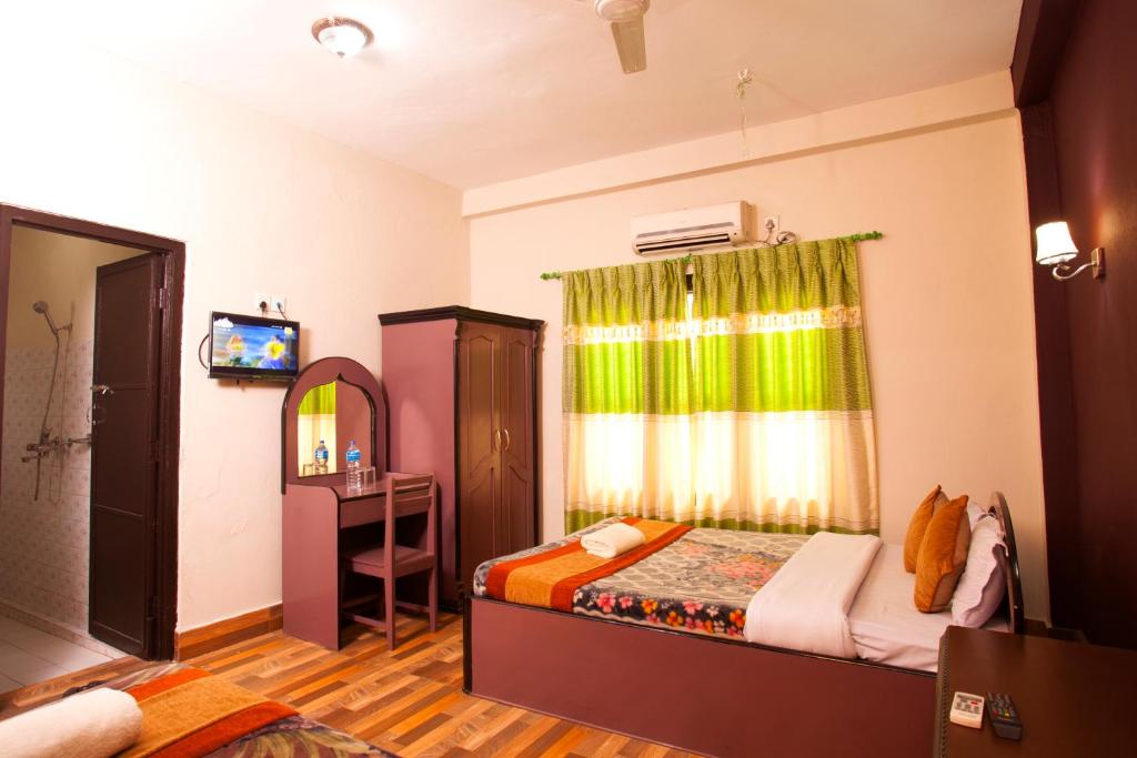a bedroom with a bed and a mirror and a television at Sauraha Resort in Sauraha