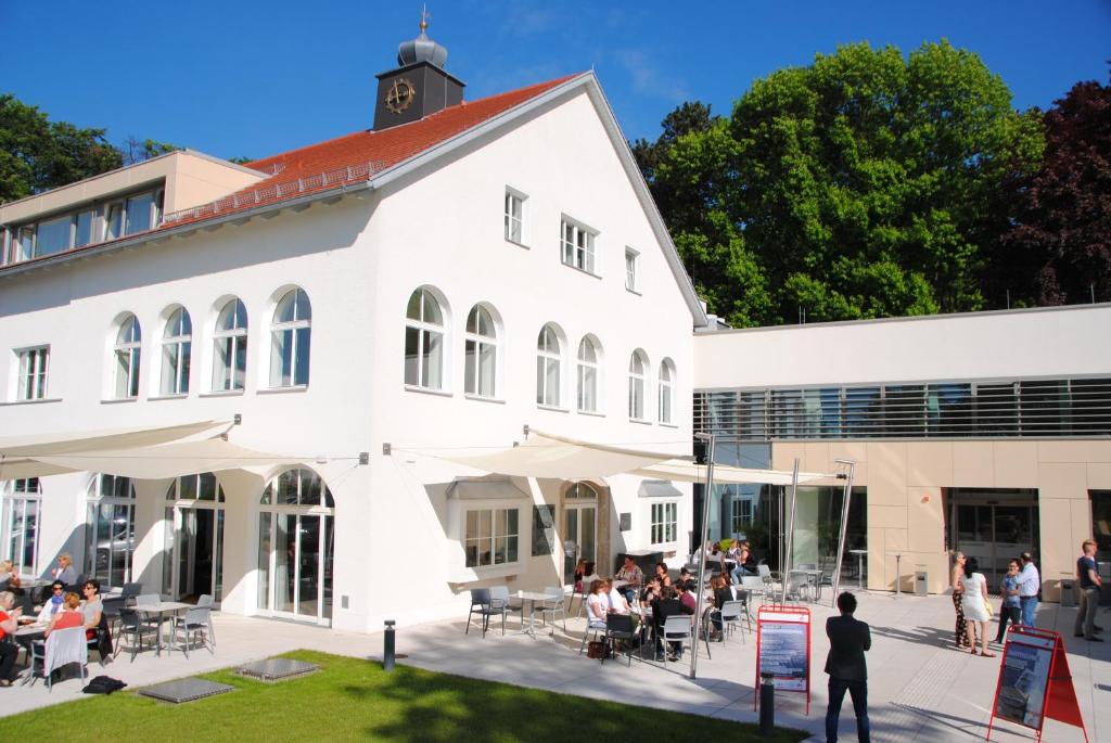 un edificio blanco con gente sentada fuera de él en Jägermayrhof en Linz