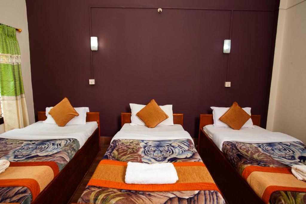 a room with two beds with orange pillows at Sauraha Resort in Sauraha