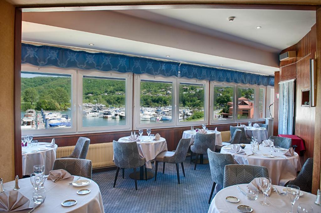 a restaurant with white tables and chairs and windows at Hôtel Le Bellevue in Les Roches-de-Condrieu