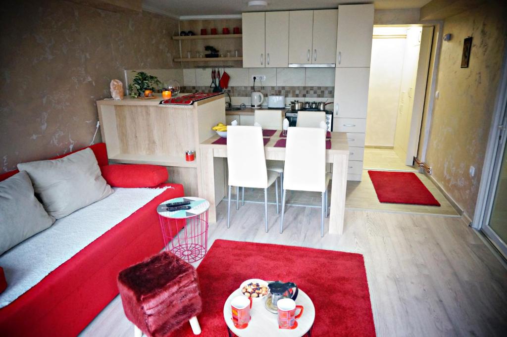 ein Wohnzimmer mit einem roten Sofa und einer Küche in der Unterkunft Apartment Kamencic in Zlatibor