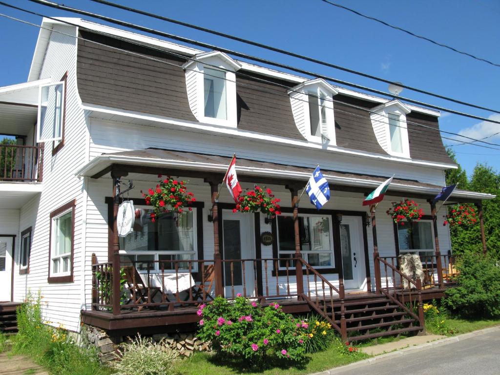 a white house with american flags on the porch at Gîte Aux Traditions in Saint-Jean-des Piles