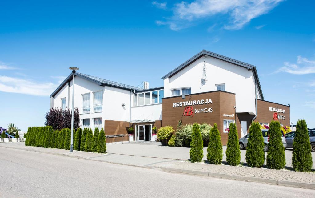 ein weißes Gebäude mit einem Schild an der Straßenseite in der Unterkunft Hotel Biancas in Kosakowo