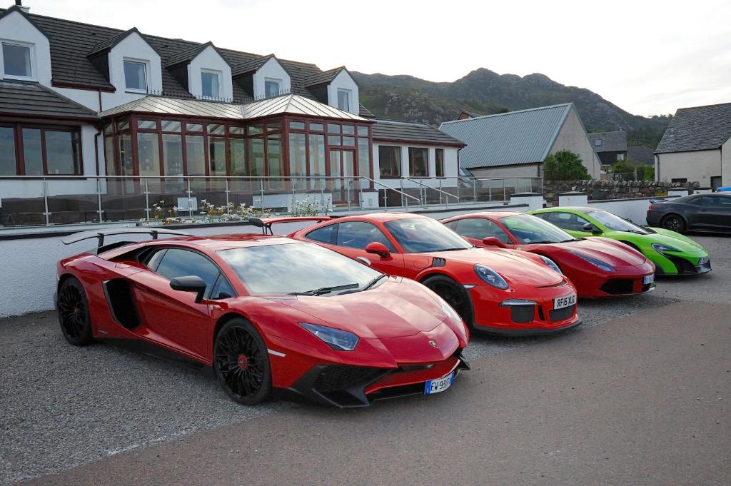 een rij rode auto's geparkeerd op een parkeerplaats bij Myrtle Bank Hotel in Gairloch
