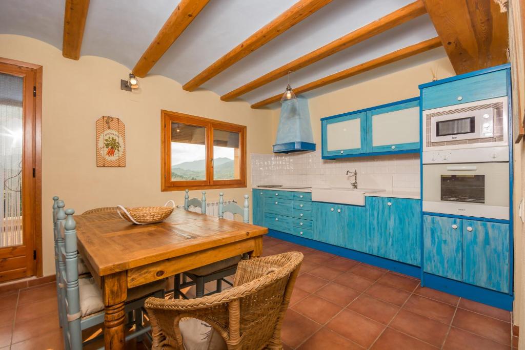 cocina con armarios azules y mesa de madera en Casas Lo Tossal, en Beceite