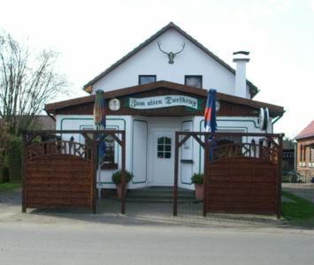 a white building with two flags in front of it at Ferienwohnung Zum Alten Dorfkrug in Schlemmin