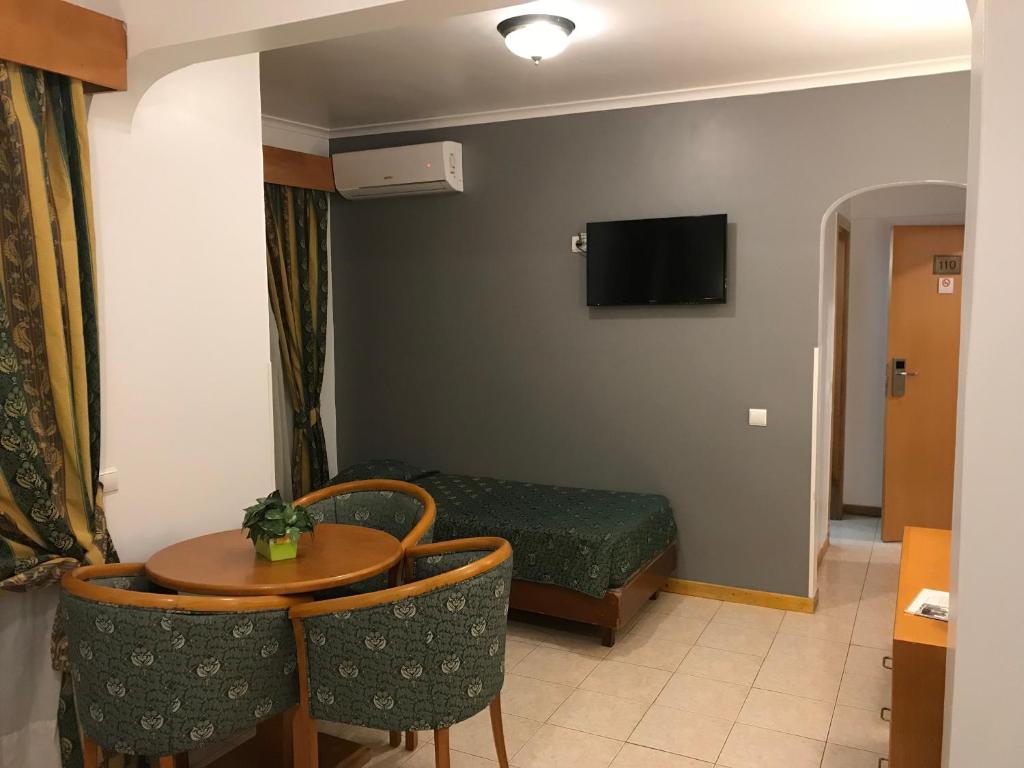 a small room with a table and a bed at Real Caparica Hotel in Costa da Caparica