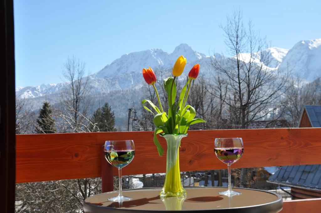 uma mesa com dois copos de vinho e um vaso com flores em Śleboda em Kościelisko