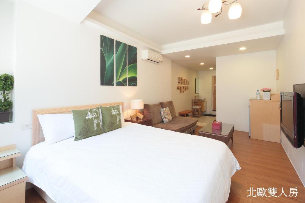 een slaapkamer met een wit bed en een woonkamer bij Happiness Yes Hostel 2 in Luodong