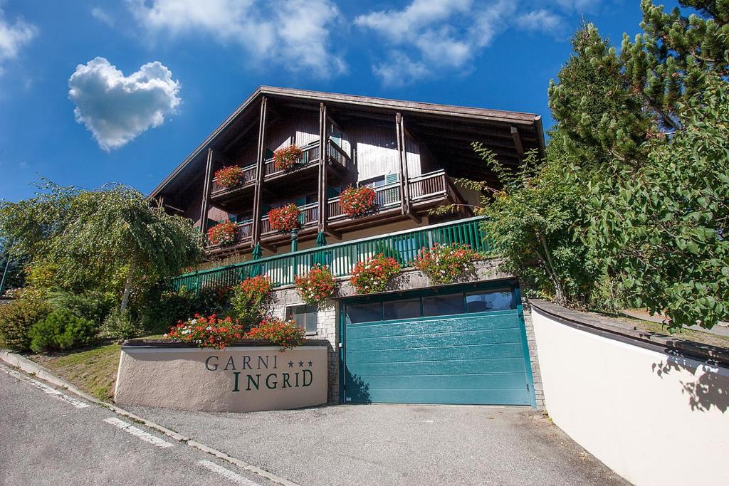 a building with a garage with a sign in front of it at Garni Ingrid in Dobbiaco