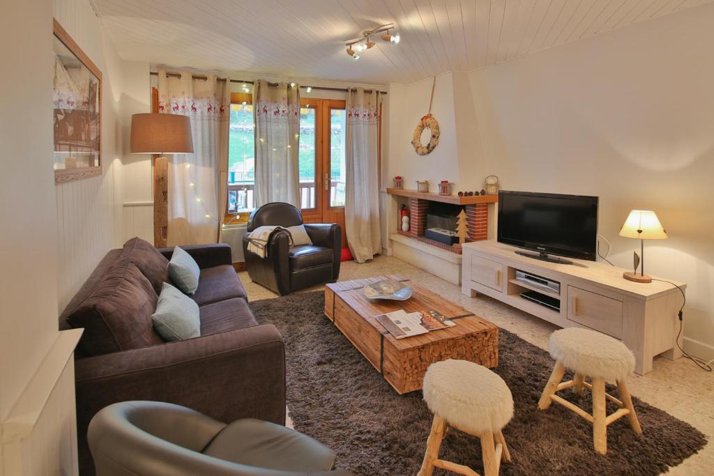 a living room with a couch and a tv at SavoieLac - Appartement Primeveres in La Clusaz
