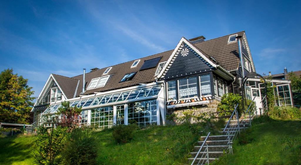 ein großes Haus mit blauen Fenstern auf einem Hügel in der Unterkunft Haus Waldwiese in Hahnenklee-Bockswiese