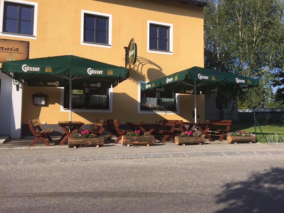 two green umbrellas and tables and chairs in front of a building at Pop's Rooms - Transilvania in Böheimkirchen
