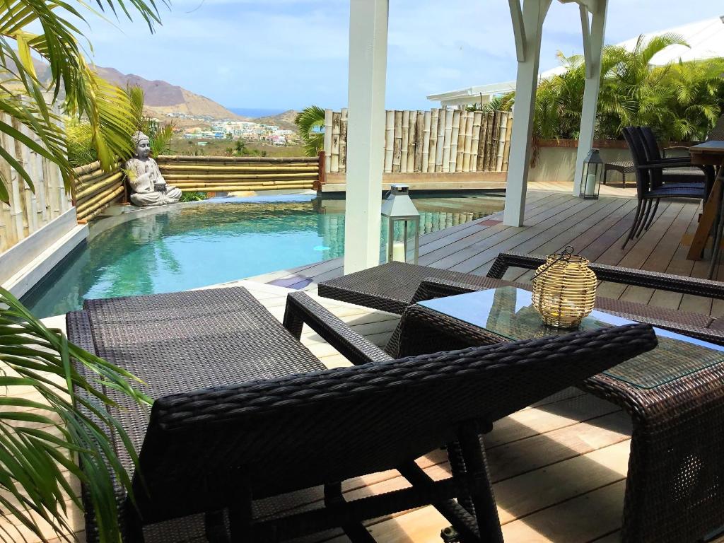 d'une terrasse avec une table et des chaises à côté de la piscine. dans l'établissement Villa La Voile Blanche, à La Baie-Orientale