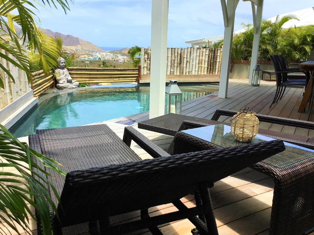 a patio with a table and chairs next to a pool at Villa La Voile Blanche in Orient Bay French St Martin