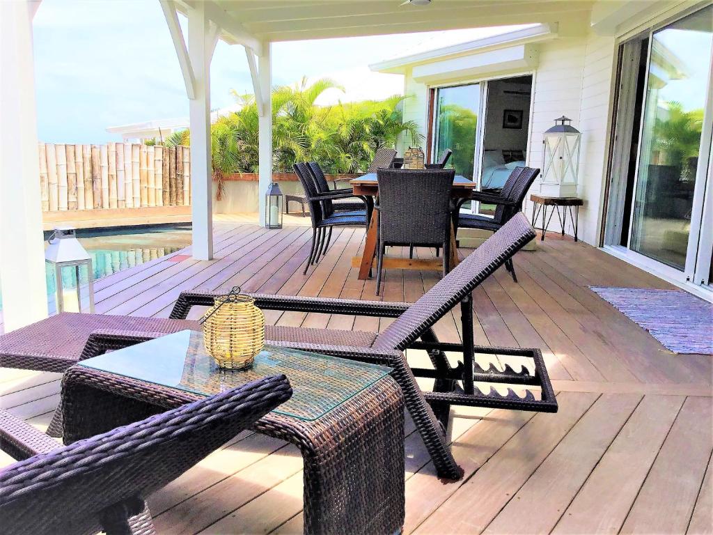 un patio avec une table et des chaises sur une terrasse dans l'établissement Villa La Voile Blanche, à La Baie-Orientale