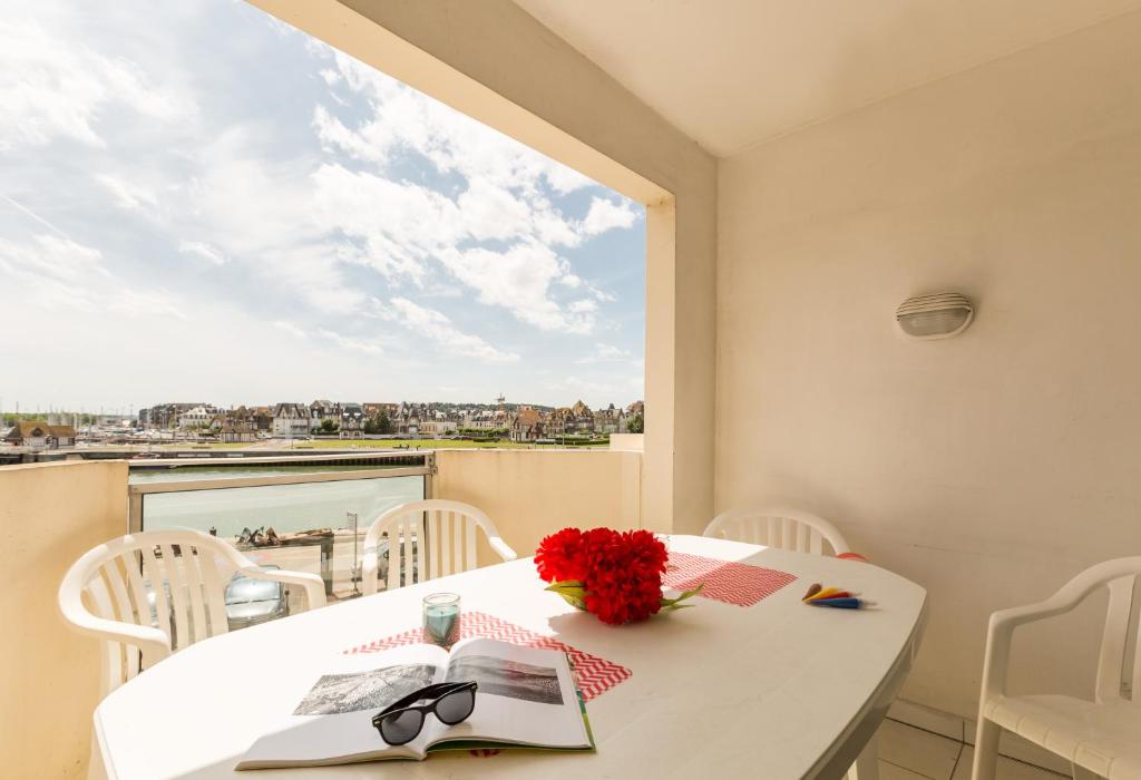 a white table with a vase of flowers and a window at SOWELL RESIDENCES Le Port in Trouville-sur-Mer