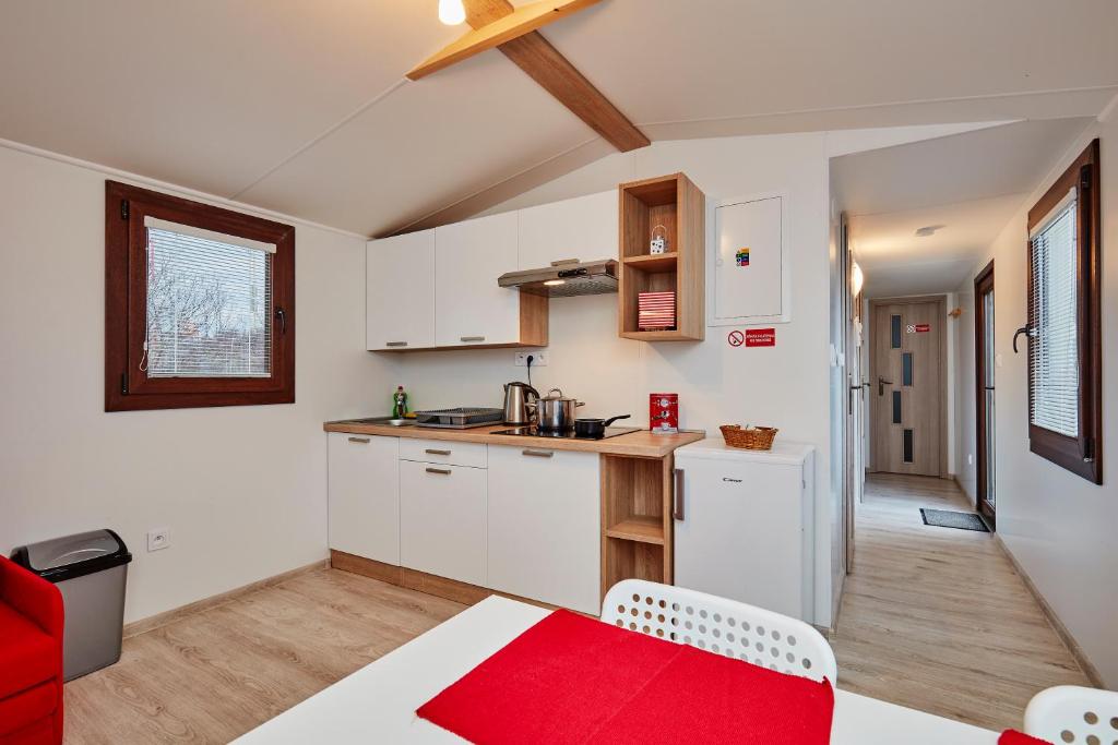 科希策Holiday houses BARCA的厨房配有白色橱柜和红色桌子