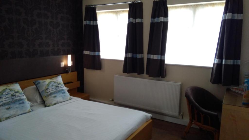 a bedroom with a bed and two windows at The Anchor Hotel & Bars in Ingoldmells
